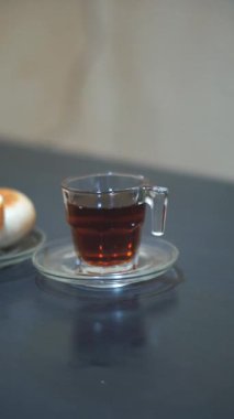Bir fincan çay ve yeşil fasulye ekmeği, siyah masada yemeye hazır.