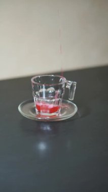 Güzel dikey video portresi Beyaz bardağa kırmızı bir içki dökülüyor