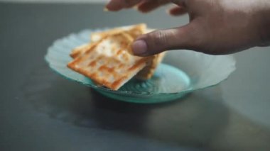 Bir adamın elleri bir tabakta bisküvi düzenliyor.
