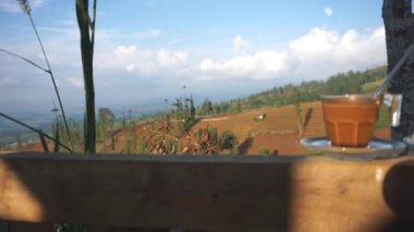 Dağlarda, beyaz bardakta bir fincan sütlü kahve ve kek.