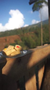 Dağlarda, beyaz bardakta bir fincan sütlü kahve ve kek.