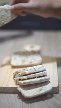 Güzel dikey video portresi, Tempeh 'i mutfak bıçağıyla dilimlemek.