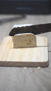 Güzel dikey video portresi, Tempeh 'i mutfak bıçağıyla dilimlemek.