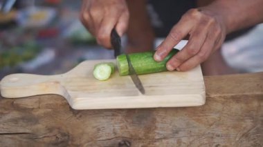 Bir adam yemek yapmak için salatalık kesiyor.