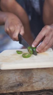 Bir adam yemek pişirmek için biber kesiyor.