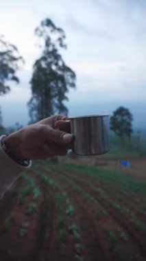 Paslanmaz bir fincanda bir fincan sade kahvenin güzel dikey video portresi ve dağ tepeleri.