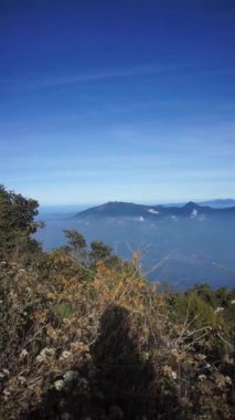 Cikuray Dağı 'nın doğal güzelliği deniz seviyesinden 2821 metre yükseklikteki mavi gökyüzünün altında uzanan bulutlarla, Cikuray Dağı, Garut Dağı, Endonezya