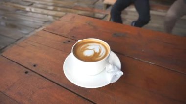 Masadaki beyaz çiçek şeklindeki bardakta bir fincan sütlü kahvenin güzel videosu