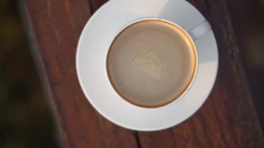 Sütlü bir fincan kahve öğleden sonra masada beyaz bir bardakta karıştırıldı.