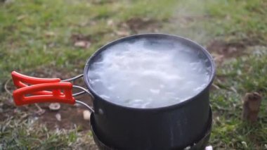Portatif bir soba kullanarak tavada beyaz pirinç pişirmek.