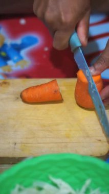 Geceleri mutfak bıçağıyla havuç doğrayan bir adam.