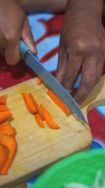 Geceleri mutfak bıçağıyla havuç doğrayan bir adam.