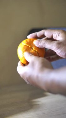 Güzel dikey bir video portresi Bir adamın eli tatlı ve olgun sarı bir portakalı soyuyor