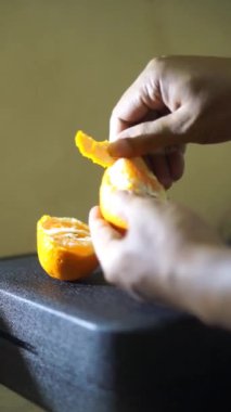 Güzel dikey bir video portresi Bir adamın eli tatlı ve olgun sarı bir portakalı soyuyor