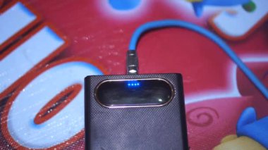 Siyah güç bankası, mavi gösterge ışığı şarj olurken yanıp sönüyor