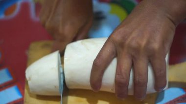 Cassava mutfak bıçağıyla kesilmiş, soyulmuş ve temiz ve beyaz görünüyor.