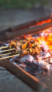 Geceleyin yanan bir kamp ateşinin közlerinde kızartılmış et ya da satay.
