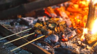 Geceleyin yanan bir kamp ateşinin közlerinde kızartılmış et ya da satay.