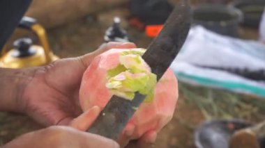 Bir adam kırmızı guava soyuyor ve kesiyor, ya da Latin Psidium guajava 'da, mutfak bıçağıyla..