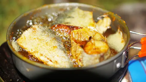 Latin Sphyraena putnamae 'deki barakuda balığı taşınabilir gaz sobasıyla kızartma tavasında kızartılıyor.