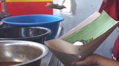 Bir kadın hizmetçi Padang restoranında yemek paketliyor..