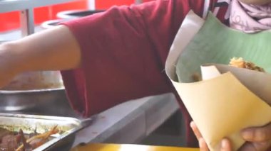 Bir kadın hizmetçi Padang restoranında yemek paketliyor..