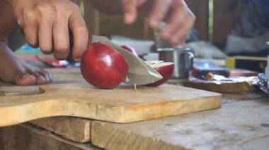 Taze kırmızı elmalar tahtadan bir hayatta kalma bıçağı kullanılarak parçalara ayrılır..