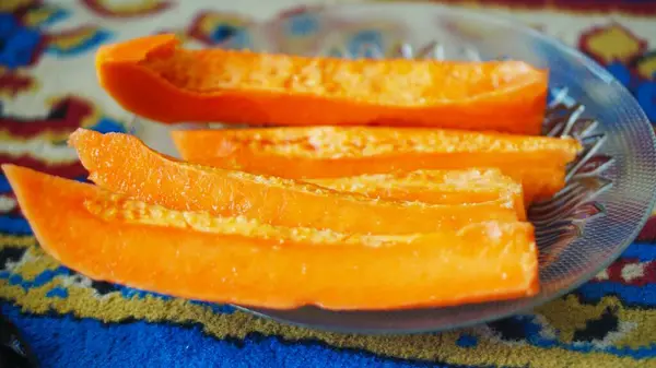 Taze olgun papaya dilimleri cam tabakta servis edilir. Meyvenin canlı rengini ve tropikal tazeliğini gözler önüne serer.