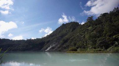 Talaga Bodas krater gölü manzarası. Endonezya 'nın batısındaki Garut şehrinde açık mavi gökyüzünün altında yemyeşil tepelerle çevrili.