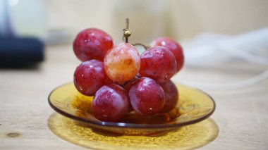 Küçük cam bir tabakta sulu kırmızı üzümler yakın plan, beslenme, vegan diyeti ve organik meyve temaları için ideal