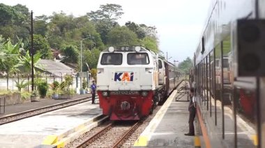 Bandung Endonezya - 13 Ağustos 2025 Farklı raylarda iki tren seti bulunan kırsal bir tren istasyonu manzarası