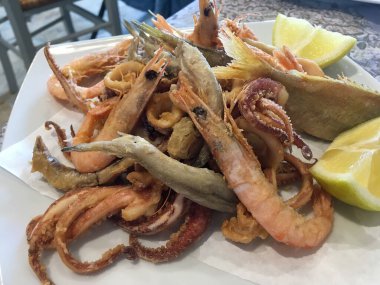 Fish and seafood fry served in a restaurant in Monopoli, Italy. Prawns, whiting, calamari among other fish and seafood, coated in flour and fried in olive oil. clipart