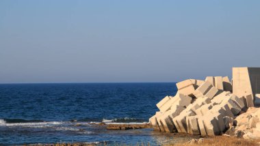 Monopoli, İtalya limanındaki koruma iskelesinin beton blokları. Adriyatik denizi ve derin mavi gökyüzü güneşli bir yaz gününde.