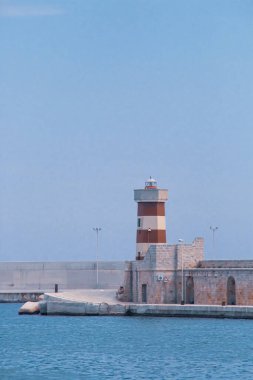 İtalya 'da Monopoli kırmızı deniz feneri. Eski liman, içindeki balıkçılık ve eğlence filosunu fırtınalardan koruyan bir duvar ve dalgakıran tarafından korunuyor..