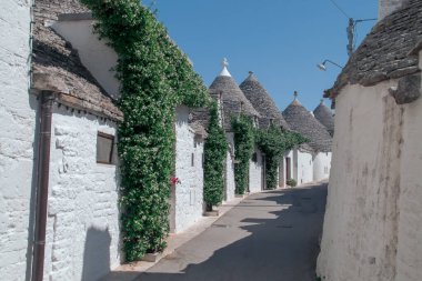 Trulli, İtalya, Alberobello 'daki Vico Francesco Lippolis sokağında. Konik taştan çatıları olan geleneksel evler zirvede bitiyor..