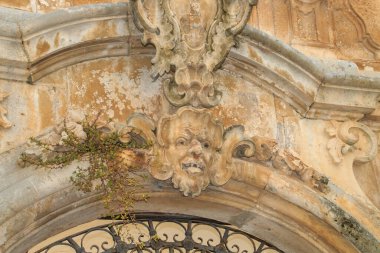 Relief above the door of the Palazzo Morelli in Locorotondo, Italy. From the 18th century in the Baroque style, the anthropomorphic mask surrounded by vines under the Morelli coat of arms stands out.