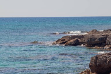 Rocky coastline with a calm sea a sunny summer day. Marine view of the Ionian sea coast, Pizzo coast in Italy.