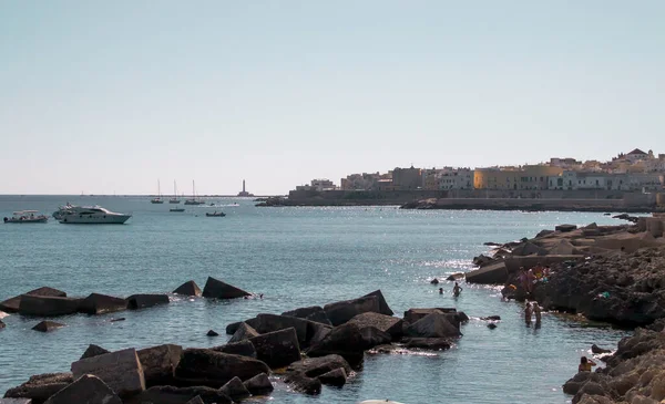在意大利加利波利加利利的伽利略大道上洗澡 落基海岸 你可以在那里晒日光浴或游泳 游艇停泊在碧绿的水面上 而圣安德烈岛灯塔则在后面 — 图库照片