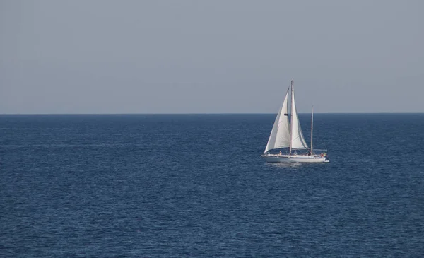 stock image Sailboat sailing on the horizon in Gallipoli, Italy. Yacht with full sails sailing in the turquoise waters of the Ionian Sea.