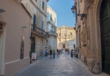 Lecce, İtalya. 06 29 2019. Giuseppe Palmieri Caddesi 'nden Aziz Mary' nin Hükmü Katedrali 'nin cephesi. Turistler gün batımında Lecce 'nin dar sokaklarında gezip geziyorlar..
