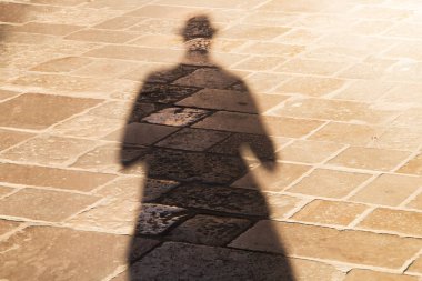 My shadow on the sunny ground of Lecce, Italy. Long shadow of a man with a hat, at sunset on a beige cobbled floor. clipart