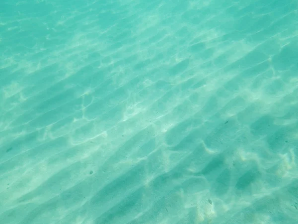 Sandy seabed through transparent water. Ripples created in the sand by the movement of water. Underwater photo in Otranto, Italy.
