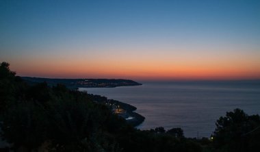 İtalya 'nın Castro kentindeki Belvedere B' den kıyı manzarası. Uzakta Santa Cesarea Terme kasabası ve şafakta İyon Denizi 'nin sakin suları..
