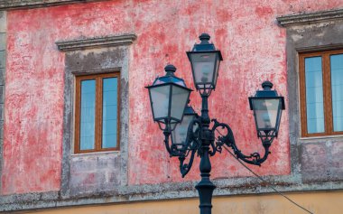 Castro, İtalya 'da klasik sokak lambası direği. Dört kollu sokak lambası eski bir evin pembe cephesinin önünde..
