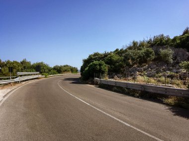 İki yönde de şeritleri olan eğri bir çıkıntı. SP358 yolu, güneşli bir yaz gününde İtalya, Castro 'nun yanında..