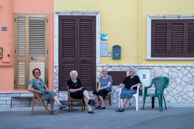 Castro, İtalya. 07 02 2019. Castro 'daki Vittorio D' Ostuni caddesinde dört yaşlı kadın. Kafkasyalı yaşlı kadınlar yazın gün batımında serinliyor..