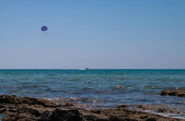 Marina di Salve, Puglia, İtalya 'daki İyon Denizi üzerinde su aktiviteleri paraşütle atlıyor. Parasailing 'de gezintiden zevk alan bir çift, motorlu tekne tarafından çekilen bir paraşüt..