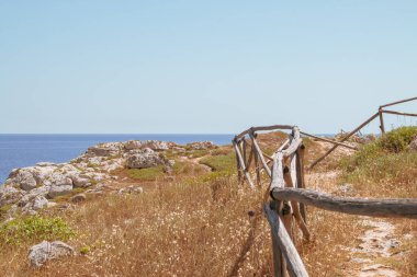 Santa Maria di Leuca, Apulia, İtalya 'daki kireçtaşı kayalıkları boyunca uzanan patika. Adriyatik Denizi ve İyon Denizi 'nin kristal berrak turkuaz sularının ayrıldığı pelerin..