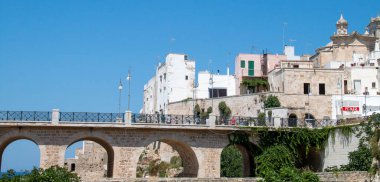 Polignano a Mare, İtalya. 07 03 2019. Monachile Koyu üzerindeki Borbonico Köprüsü. Güneşli bir yaz gününde şehrin tarihi bölgesinde bulunan köprüde yürüyen turistler.