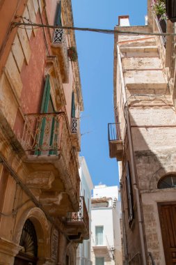 Eski şehrin dar sokakları, Annunziata Caddesi, Polignano a Mare, İtalya. Geleneksel yapıdan oluşan eski evler, sıcak yaz boyunca gölge oluşturmak için birbirine kenetlenmişti..